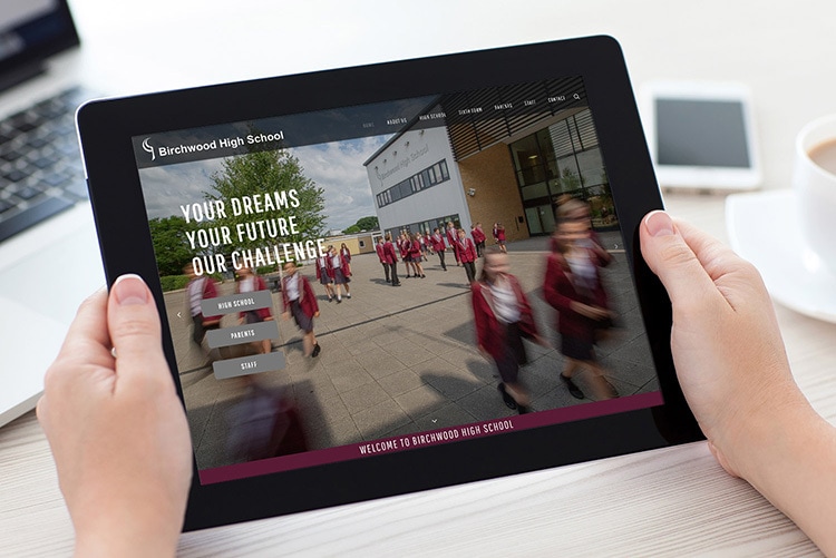 A person holding a tablet browsing through Birchwood High School website design