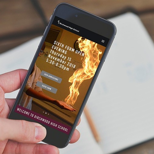 A person holding mobile displaying Birchwood High School responsive website