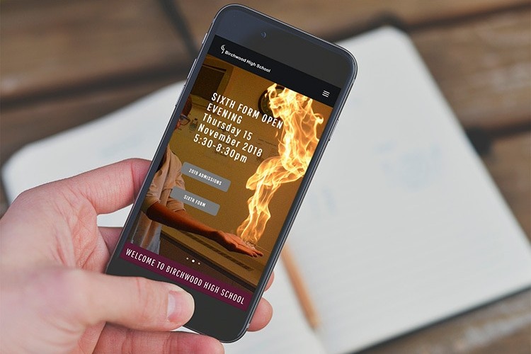 A person holding mobile displaying Birchwood High School responsive website