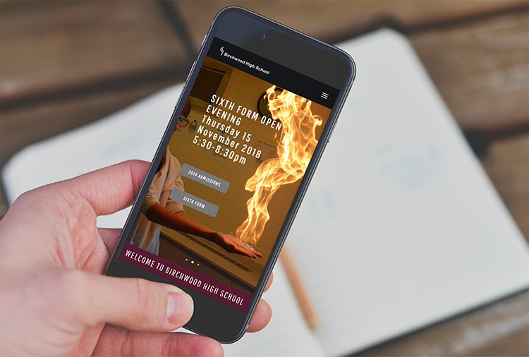 A person holding mobile displaying Birchwood High School responsive website