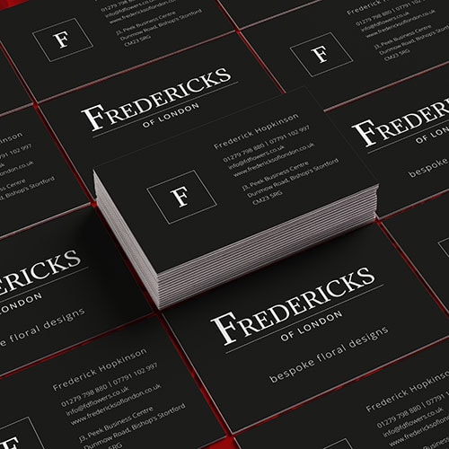 Fredericks of London branded business cards stacked and spread on top of red roses Thumbnail