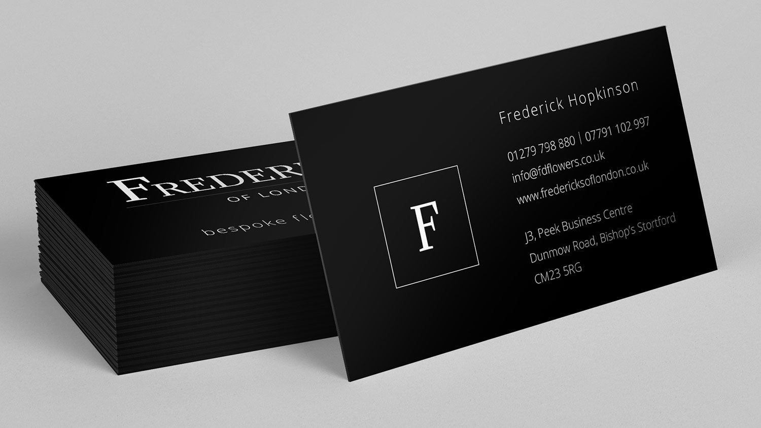 Business card resting on stack of business cards for Fredericks of London branding design