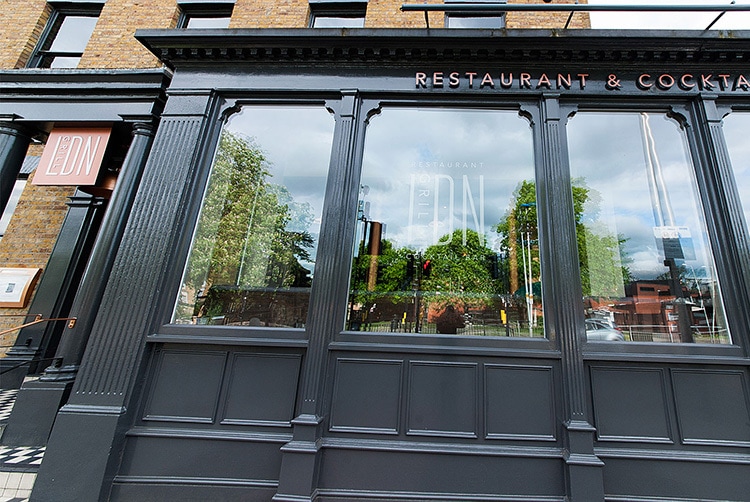 Exterior branding showing illuminated sign and window decal of LDN Grill Logo design