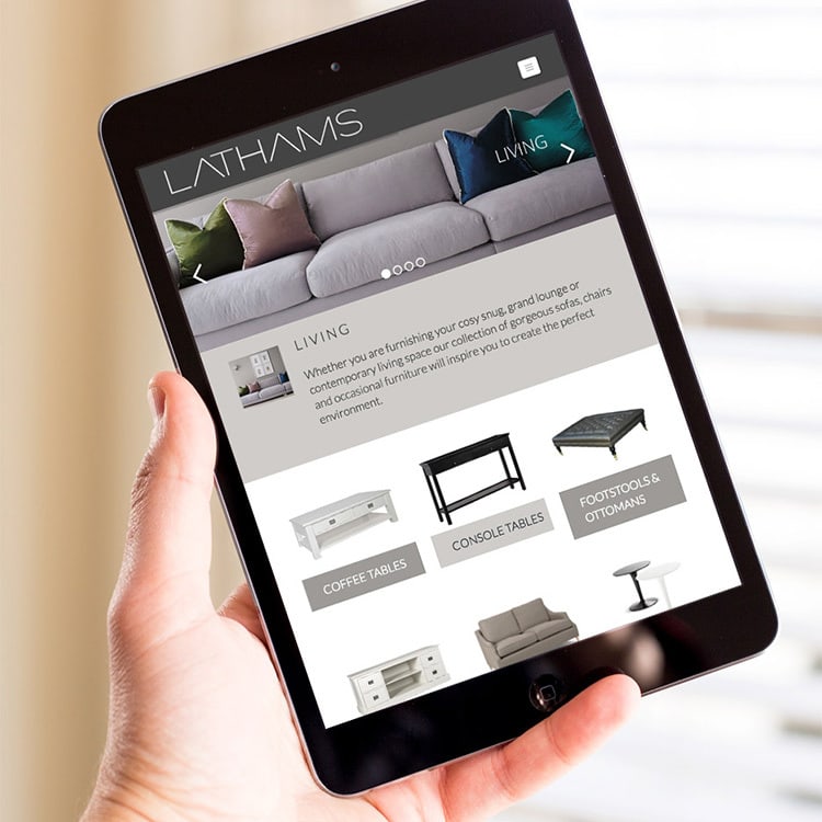 A person holding a tablet displaying the Lathams homepage website design