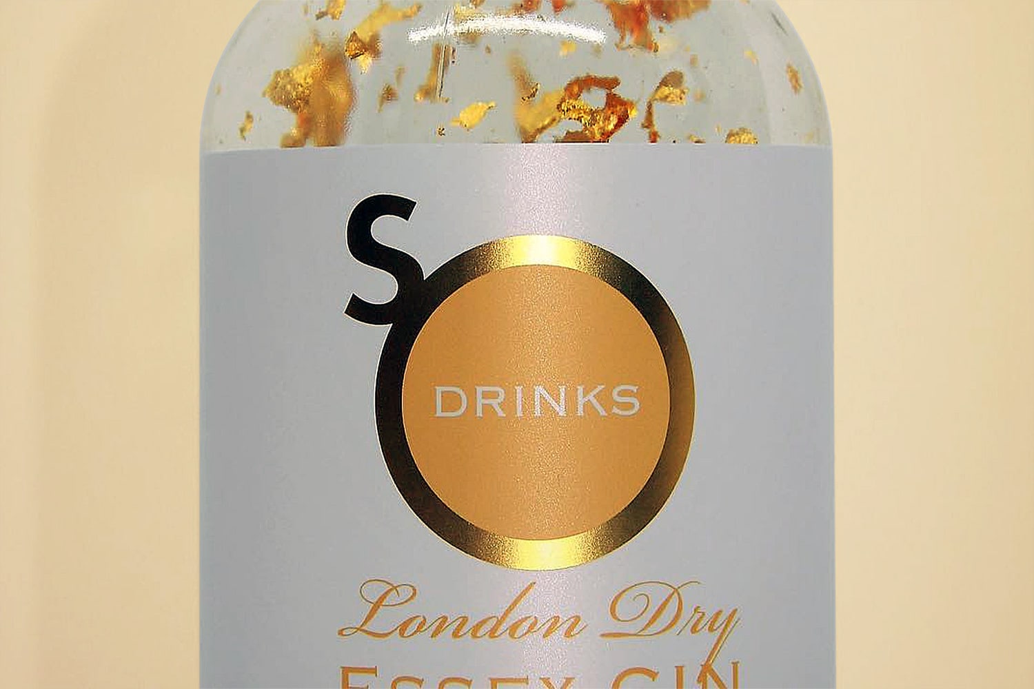Close up of Essex Gin with gold shavings and So Drinks branding in a gold foil finish orange background