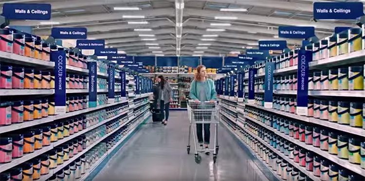 A woman with a trolley walking through paint selection photography for Wickes